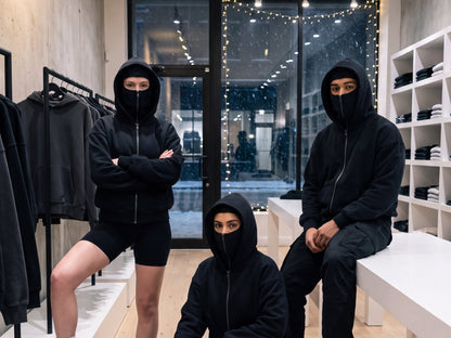 Three people in a clothing store wearing the Cover Hoodie zipped up to the eyes