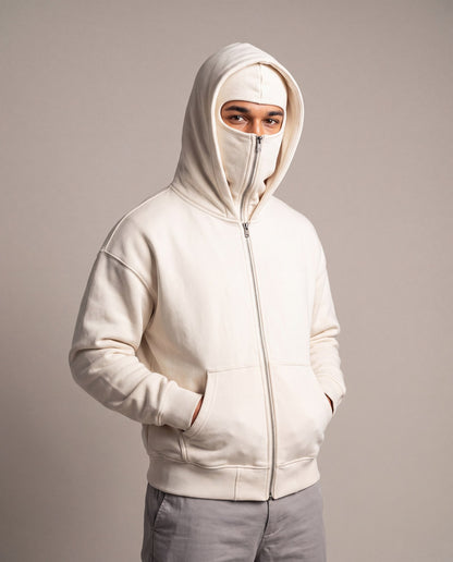 The Cover Hoodie in white, zipped up to just below the eyes, studio photo